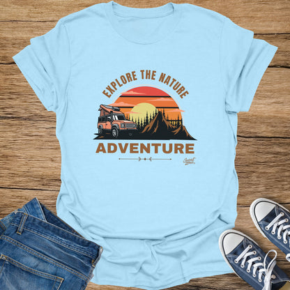 Light blue t-shirt graphic with orange camper van, mountains, sunset, and text "EXPLORE THE NATURE ADVENTURE".