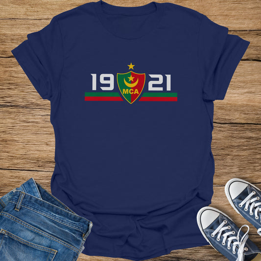 Navy t-shirt with "19 MCA 21" and shield logo on a wooden background.