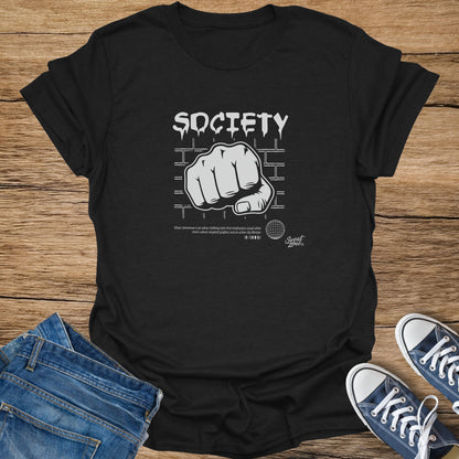 Black t-shirt with "SOCIETY" and a fist graphic, brick background.