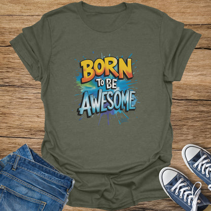 Olive green t-shirt with "BORN TO BE AWESOME" graphic on a wooden background.
