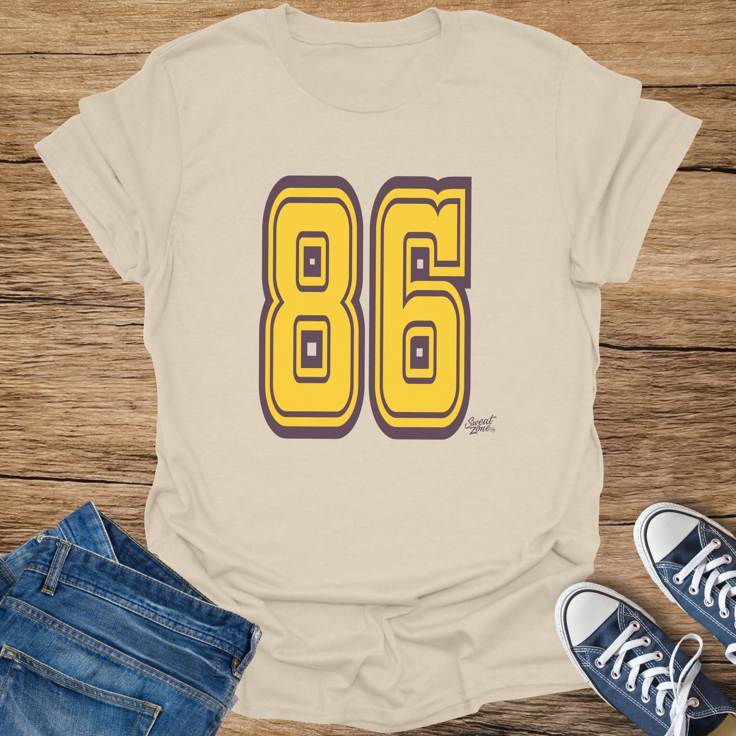 Tan t-shirt with oversized yellow 86 graphic and small "Sweat Zone" logo.