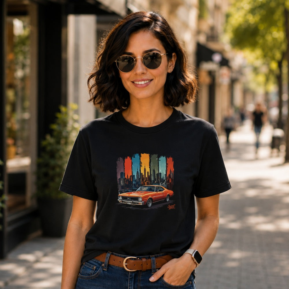 Black t-shirt with orange classic car design against a city skyline.